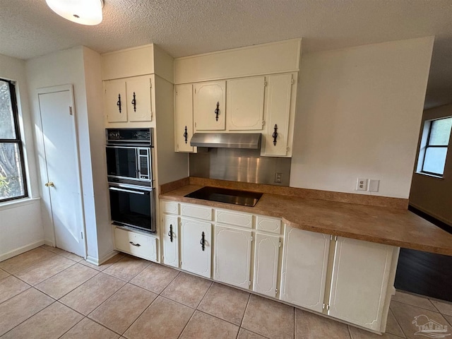 kitchen featuring black appliances, plenty of natural light, white cabinets, and light tile patterned floors