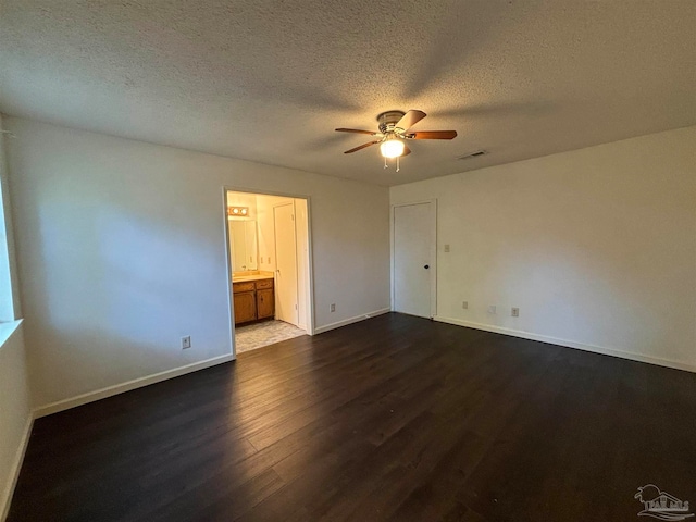 unfurnished bedroom with ceiling fan, dark hardwood / wood-style flooring, ensuite bathroom, and a textured ceiling