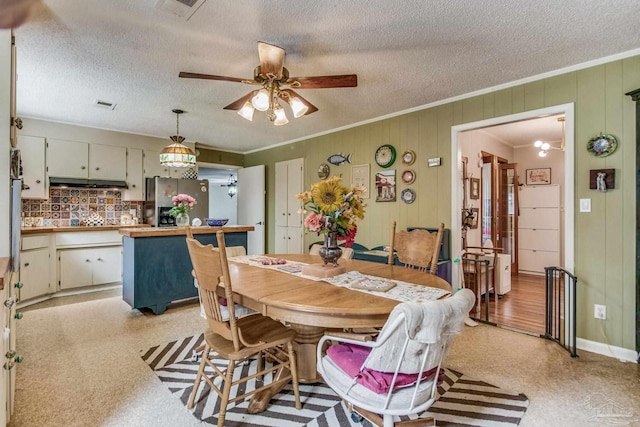 dining space with ceiling fan, ornamental molding, and a textured ceiling