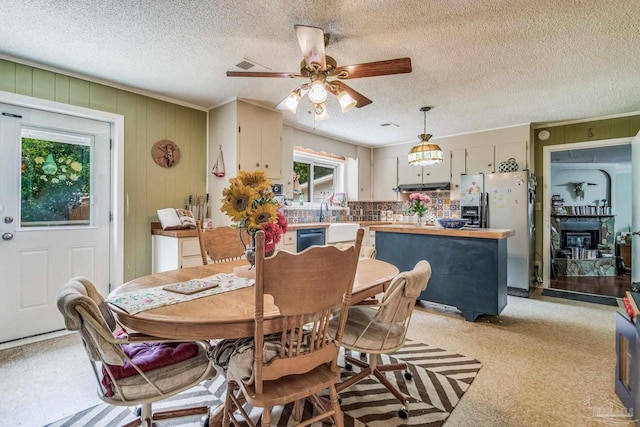 dining space featuring light colored carpet, a textured ceiling, and ceiling fan