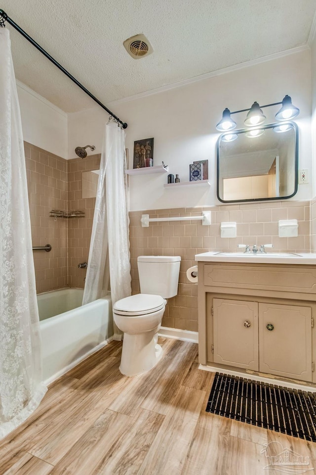 full bathroom with hardwood / wood-style floors, shower / bathtub combination with curtain, a textured ceiling, and tile walls