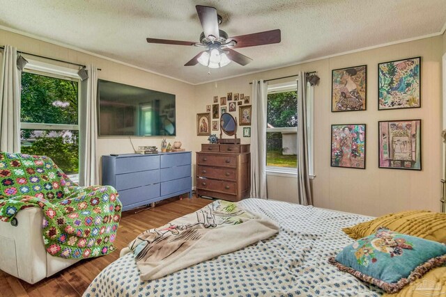 bedroom with ceiling fan, crown molding, wood-type flooring, and a textured ceiling