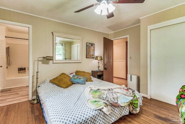 bedroom featuring connected bathroom, hardwood / wood-style flooring, ceiling fan, crown molding, and a textured ceiling