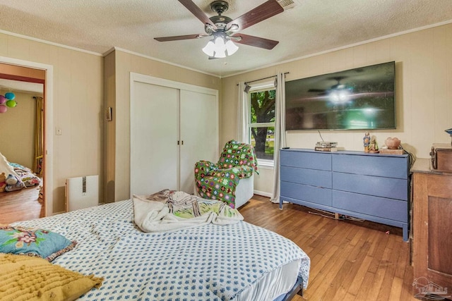 bedroom with crown molding, a textured ceiling, a closet, and hardwood / wood-style flooring