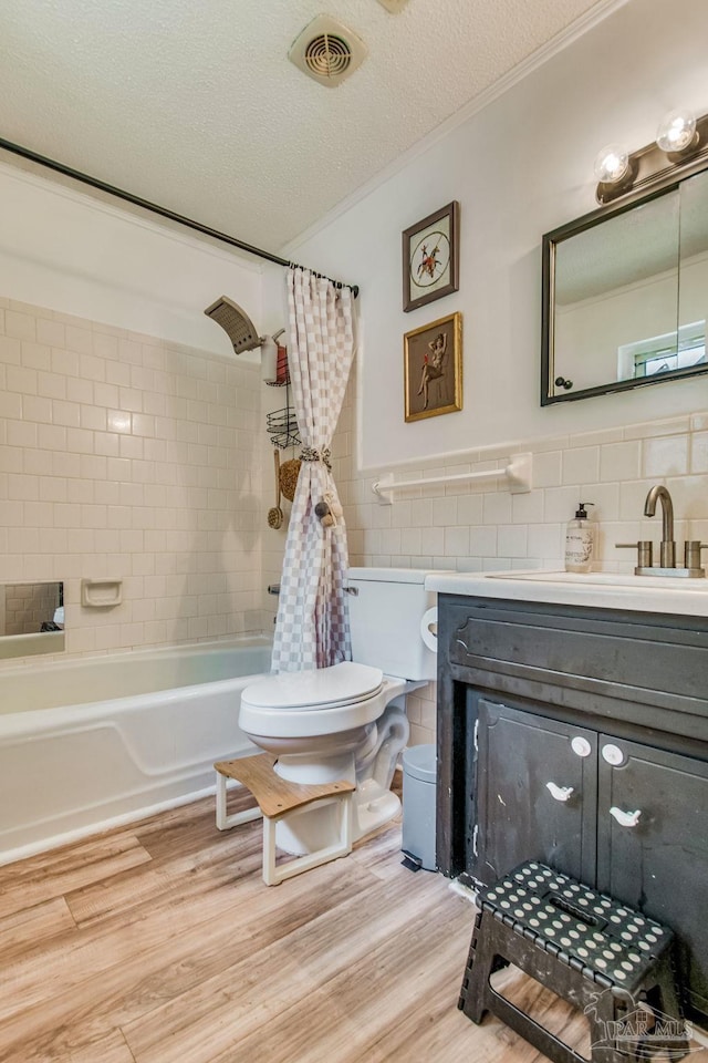 full bathroom featuring hardwood / wood-style flooring, tile walls, vanity, a textured ceiling, and shower / bath combo with shower curtain