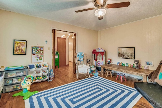 recreation room featuring ceiling fan, ornamental molding, hardwood / wood-style floors, and a textured ceiling