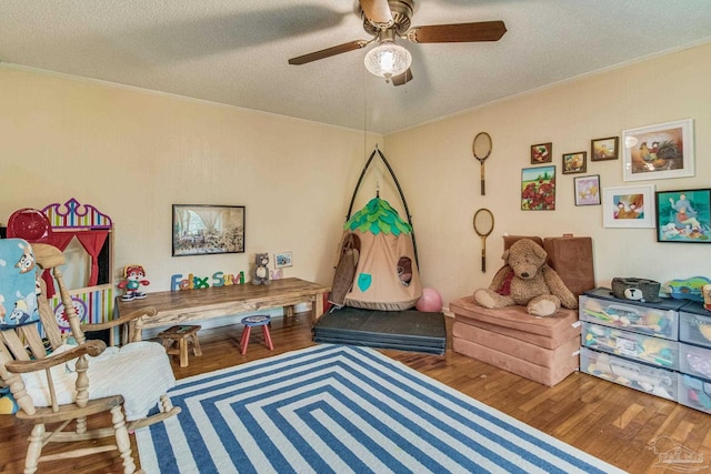 rec room featuring ceiling fan, crown molding, wood-type flooring, and a textured ceiling