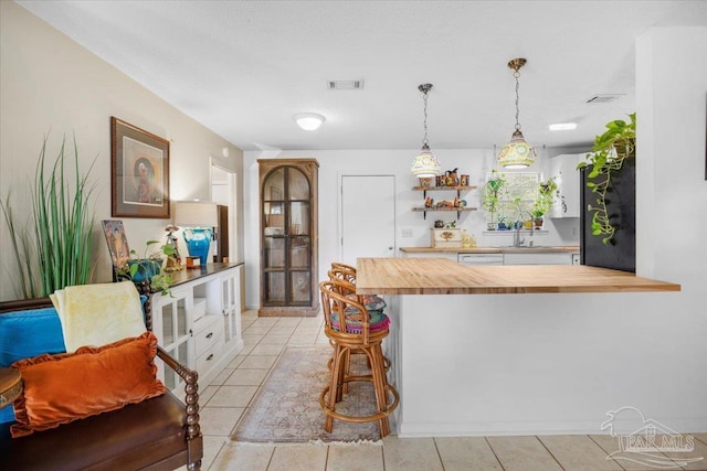 1404 Stanford Rd, Gulf Breeze, FL 32563 - kitchen featuring butcher block counters, a sink, visible vents, a kitchen breakfast bar, and pendant lighting