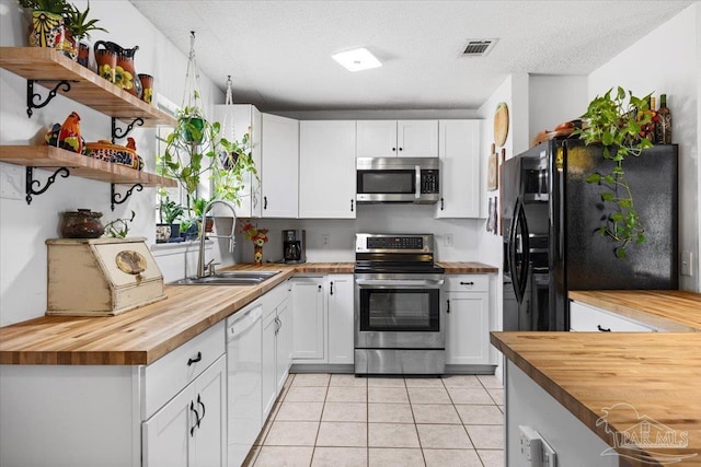 1404 Stanford Rd, Gulf Breeze, FL 32563 - kitchen with white cabinets, butcher block counters, appliances with stainless steel finishes, a sink, and light tile patterned flooring