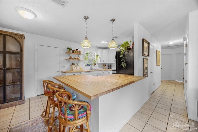 1404 Stanford Rd, Gulf Breeze, FL 32563 - kitchen with light tile patterned floors, butcher block counters, a kitchen bar, and visible vents