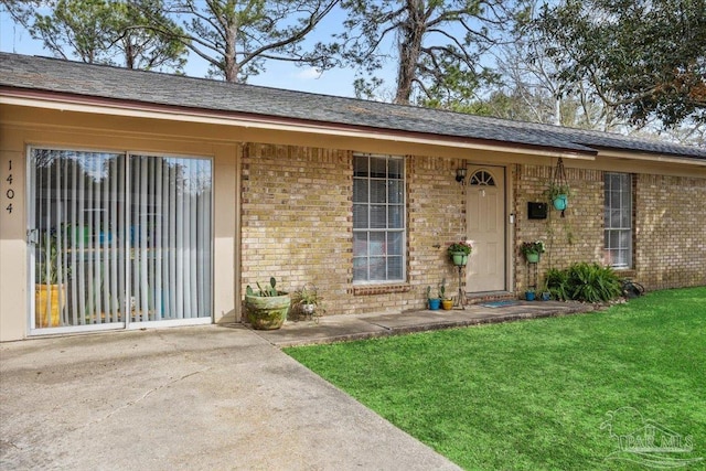 1404 Stanford Rd, Gulf Breeze, FL 32563 - view of exterior entry featuring a yard and brick siding