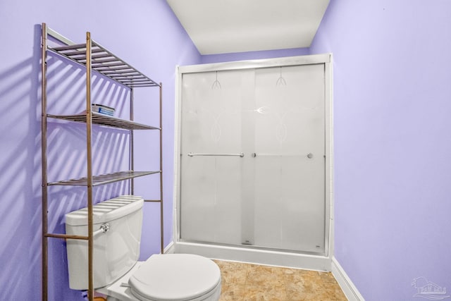 bathroom with a shower with shower door and toilet