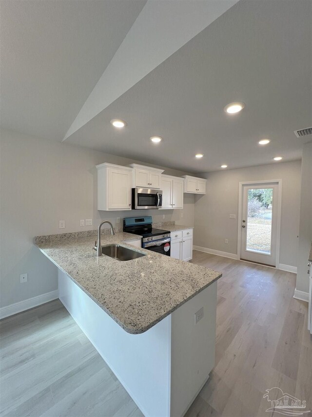 kitchen with lofted ceiling, ceiling fan with notable chandelier, sink, kitchen peninsula, and stainless steel appliances