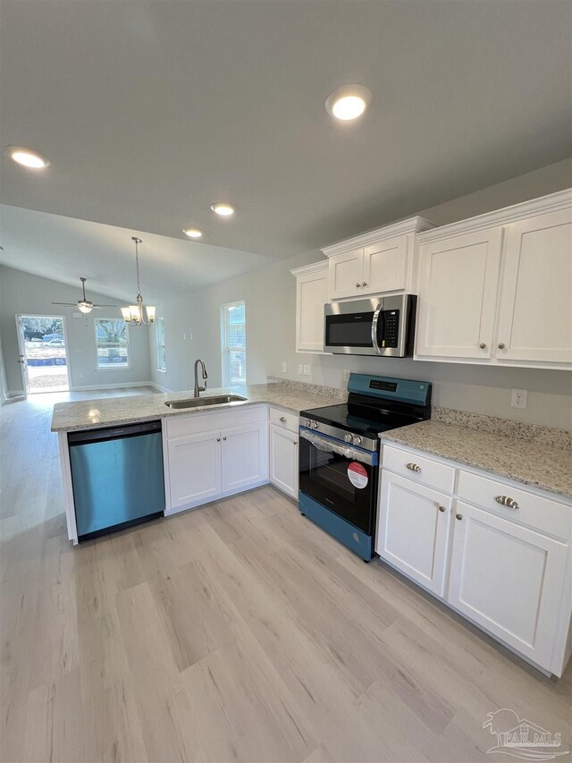 kitchen with gray cabinetry, stainless steel appliances, sink, pendant lighting, and lofted ceiling