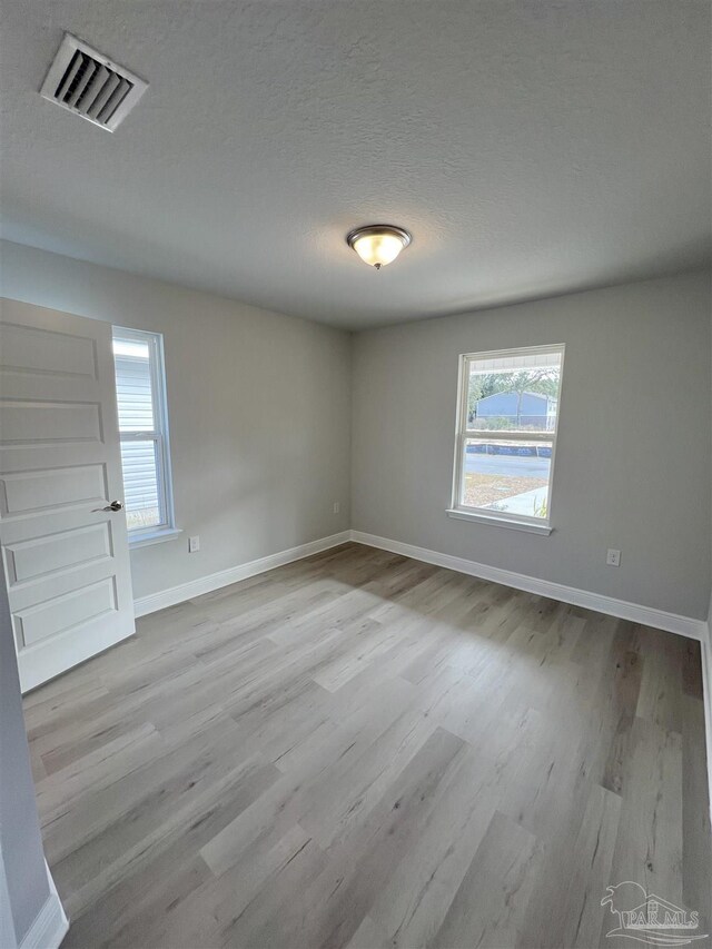 spare room featuring a tray ceiling, ceiling fan, and light wood-type flooring