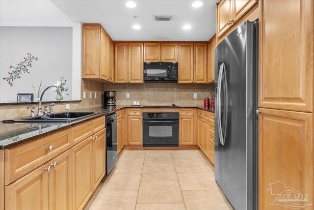 kitchen with sink, backsplash, dark stone countertops, light tile patterned floors, and black appliances