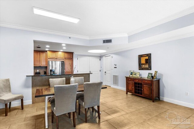 dining area with crown molding and light tile patterned floors