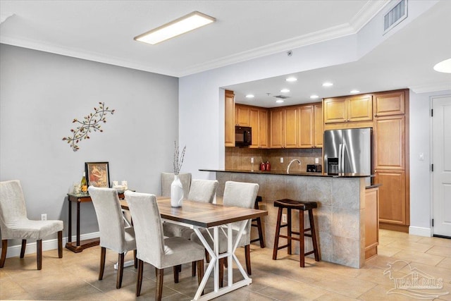 tiled dining room featuring sink and ornamental molding