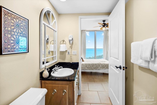 bathroom featuring vanity, a water view, tile patterned flooring, ceiling fan, and toilet