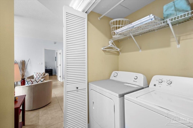 clothes washing area with light tile patterned flooring and washing machine and dryer