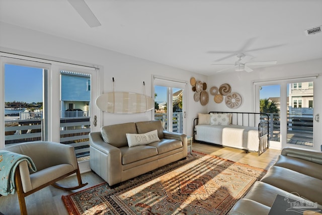 living room featuring a ceiling fan, visible vents, and wood finished floors