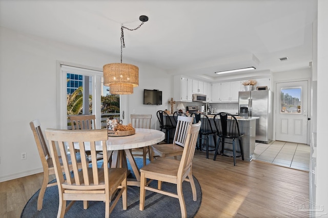 dining space with baseboards, plenty of natural light, visible vents, and light wood-style floors