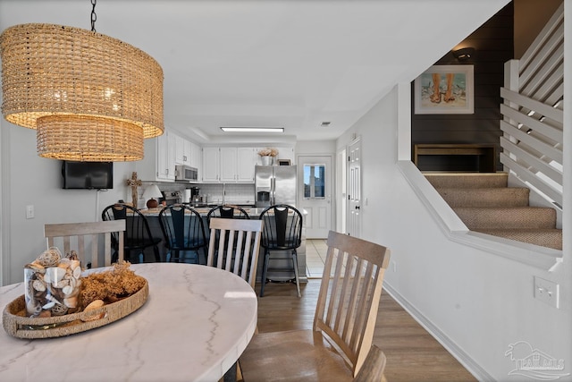 dining space with stairs, light wood-style flooring, and baseboards