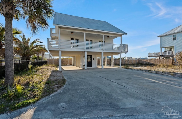 view of front of property featuring driveway, a balcony, metal roof, fence, and a carport