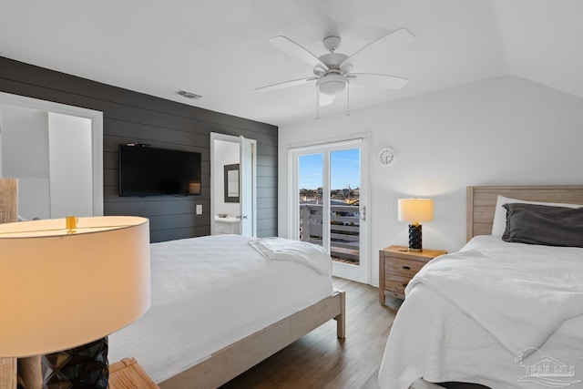 bedroom featuring visible vents, lofted ceiling, ceiling fan, wood finished floors, and access to outside