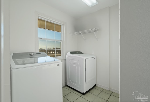 washroom featuring laundry area, light tile patterned flooring, washing machine and dryer, and baseboards