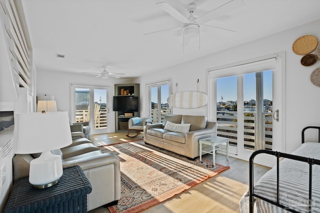 living area featuring a ceiling fan, visible vents, and wood finished floors