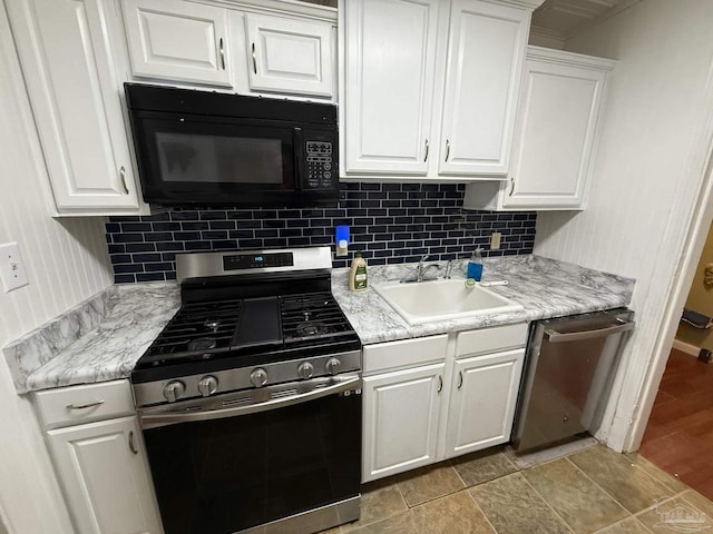 kitchen with appliances with stainless steel finishes, white cabinets, a sink, and tasteful backsplash