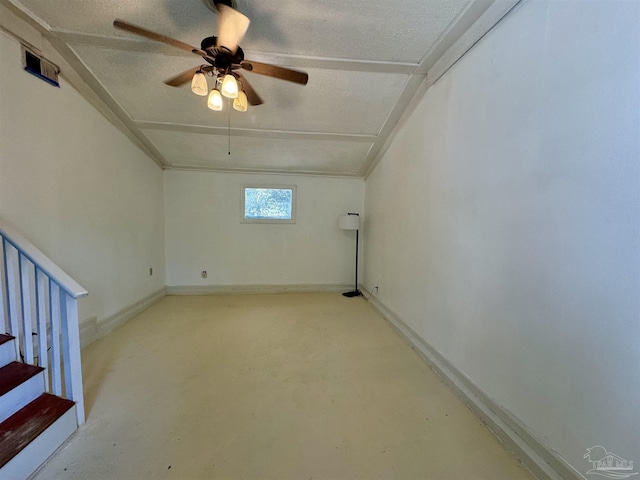 spare room with a textured ceiling, ceiling fan, concrete flooring, baseboards, and stairs