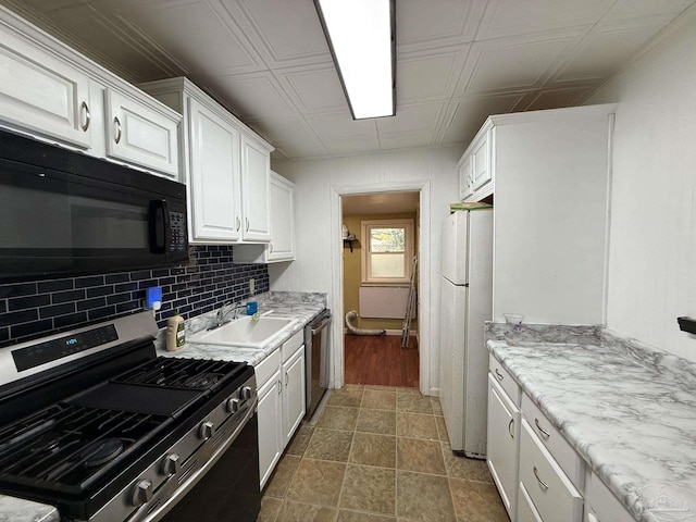 kitchen with an ornate ceiling, stainless steel appliances, decorative backsplash, white cabinets, and a sink