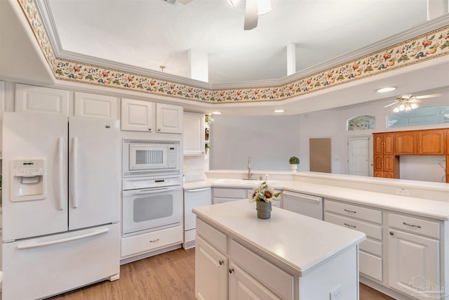 kitchen featuring light countertops, a ceiling fan, a sink, white appliances, and a peninsula