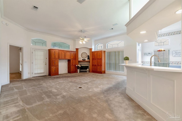 unfurnished living room with visible vents, a ceiling fan, light carpet, a sink, and baseboards