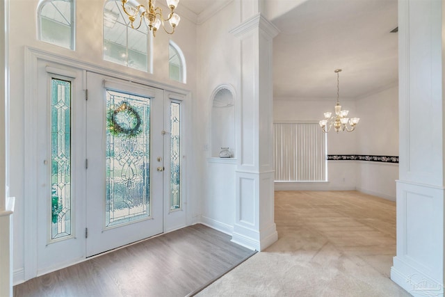 foyer entrance featuring an inviting chandelier, crown molding, and light carpet