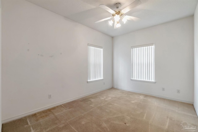 spare room with ceiling fan, baseboards, and light colored carpet