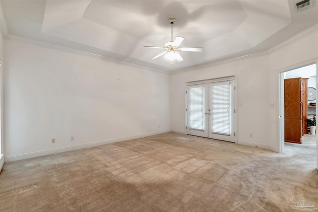 spare room with a raised ceiling, visible vents, a ceiling fan, and light colored carpet
