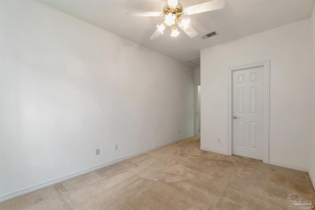 spare room with light carpet, a ceiling fan, visible vents, and baseboards
