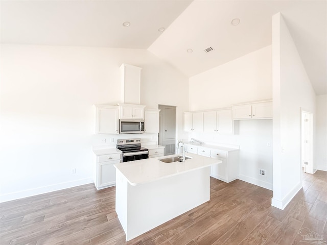 kitchen with a kitchen island with sink, sink, appliances with stainless steel finishes, light hardwood / wood-style floors, and white cabinetry