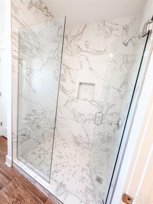 bathroom with a shower with door and wood-type flooring