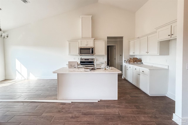 kitchen with white cabinets, an island with sink, dark hardwood / wood-style floors, and appliances with stainless steel finishes