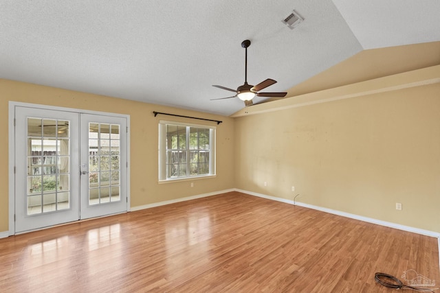 unfurnished room featuring a textured ceiling, french doors, lofted ceiling, light wood-type flooring, and ceiling fan