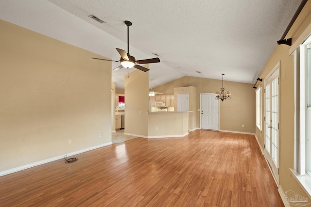 unfurnished living room with lofted ceiling, ceiling fan with notable chandelier, a textured ceiling, and light hardwood / wood-style flooring