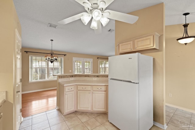 kitchen featuring ceiling fan with notable chandelier, white refrigerator, light tile patterned floors, and pendant lighting