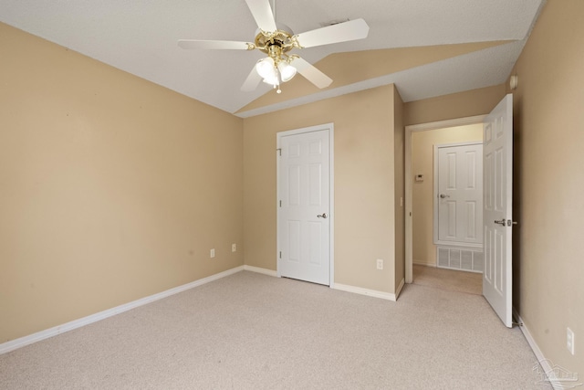 unfurnished bedroom featuring ceiling fan, vaulted ceiling, and light colored carpet