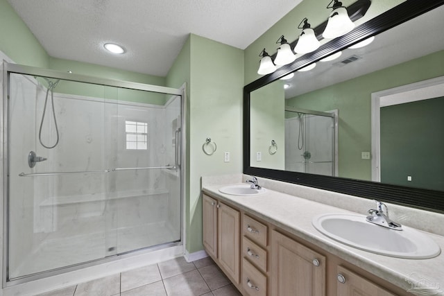 bathroom featuring a textured ceiling, a shower with door, tile patterned floors, and vanity