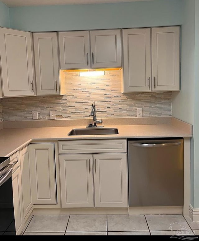 kitchen featuring dishwasher, sink, light tile patterned floors, stove, and white cabinets