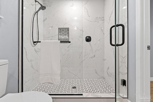 bathroom featuring a shower with shower door and toilet